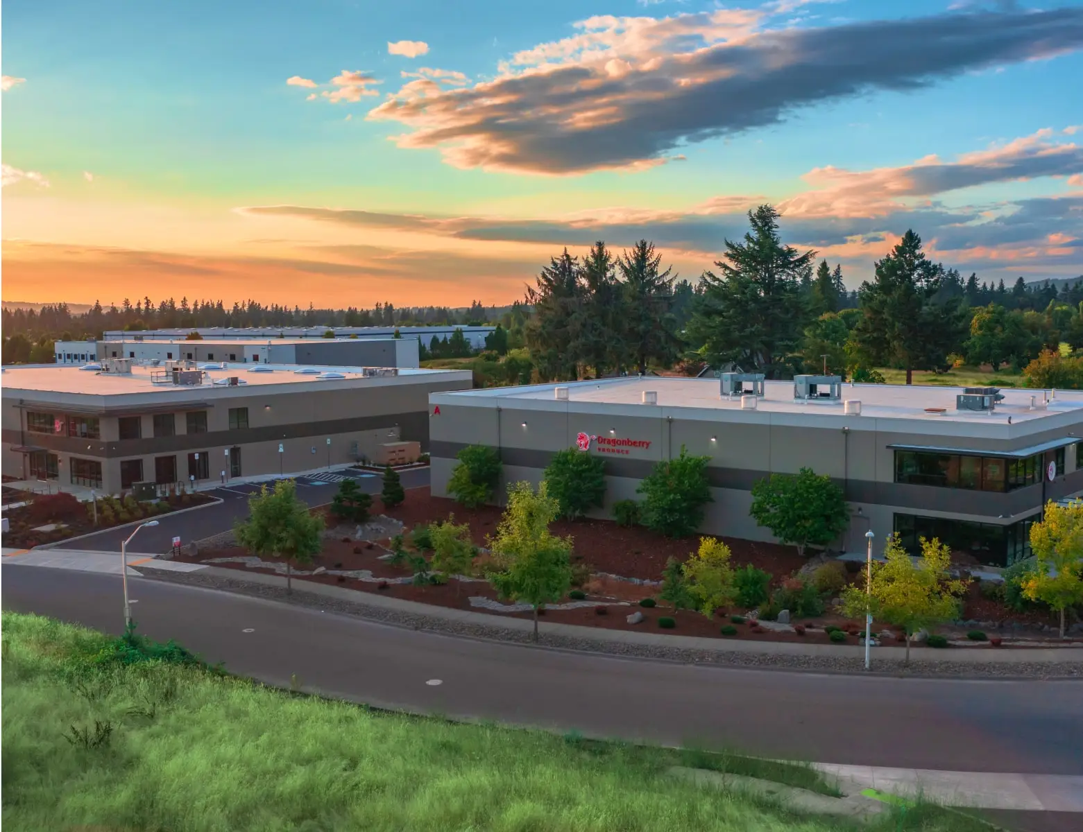Building sits at sunset. Dragonberry Produce is displayed on the side. Landscaped grounds surround it.