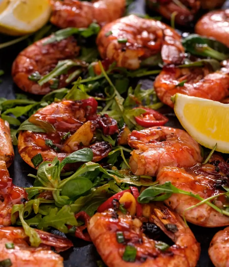 Grilled shrimp, tossed in a glaze, atop greens.
